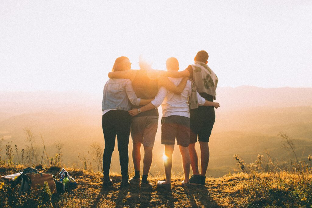 friends on a hike, arma around eachother enjoying the view